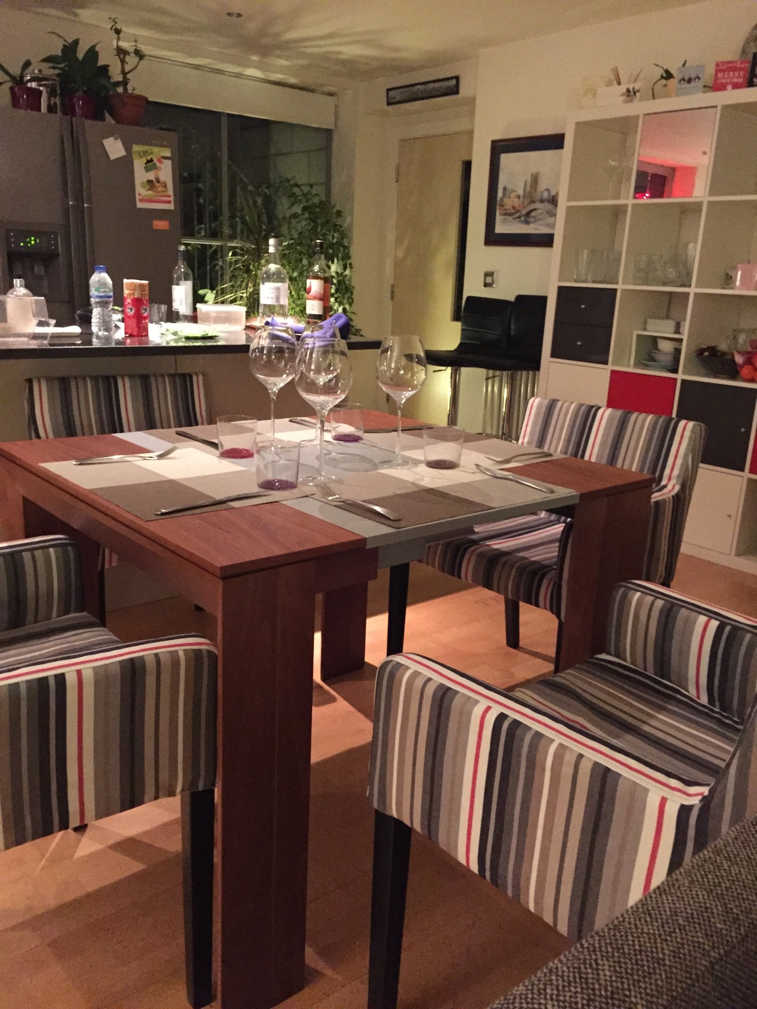 Dining table set for an evening meal, kitchen and reception beyond