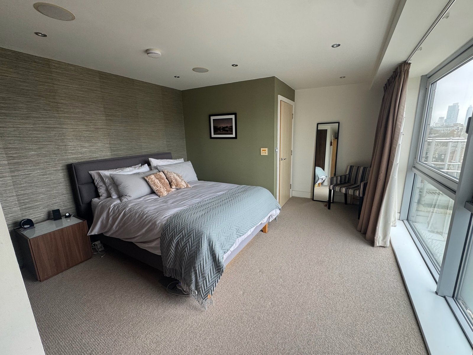 Principal bedroom with king bed, accent wall and floor-to-ceiling window