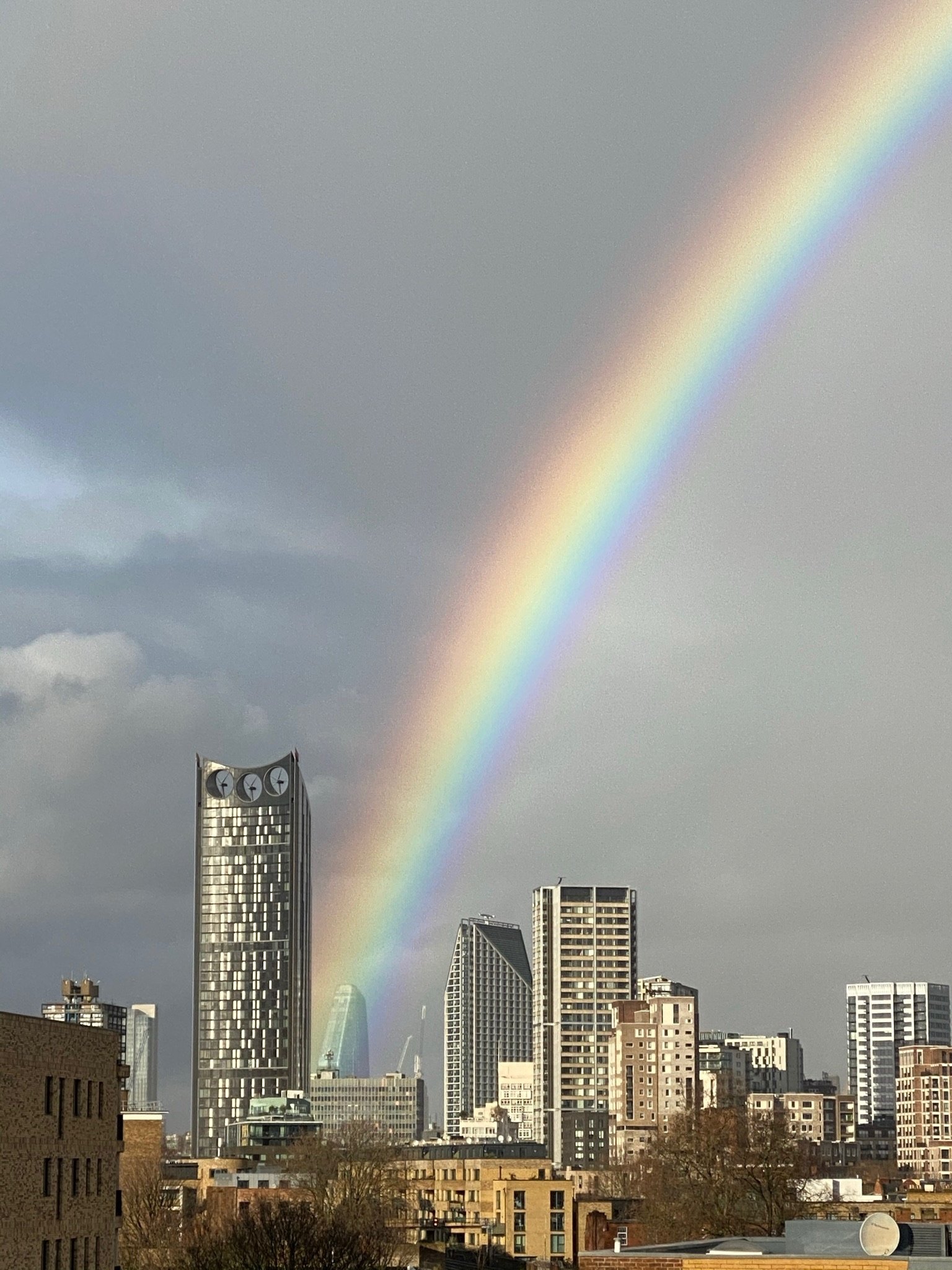 Rainbow rising above the Strata tower and central London skyline after rain